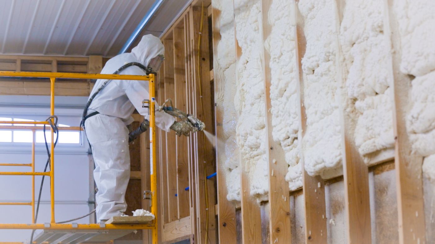 Contractor applying spray foam insulation in a commercial metal building