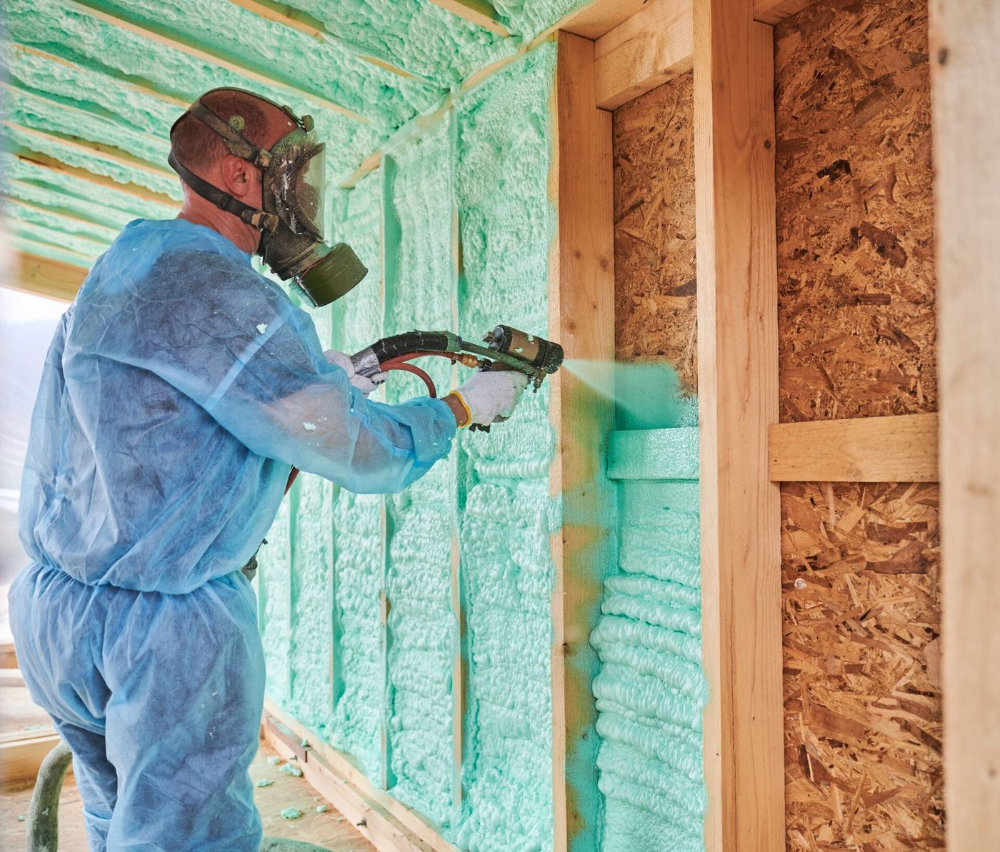 Contractor applying spray foam insulation to a wall in new construction